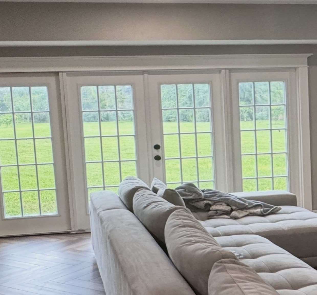 New white French doors with grids and matching sidelites, trimmed out in a finished room